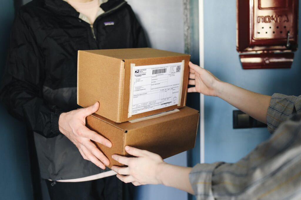 pexels-photo-4440774 Close-up of hands exchanging cardboard boxes indoors, symbolizing delivery service.